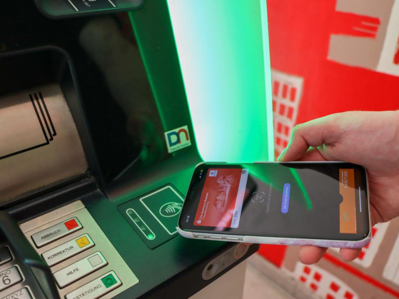 Handy wird an den NFC Bereich eines Geldautomaten gehalten