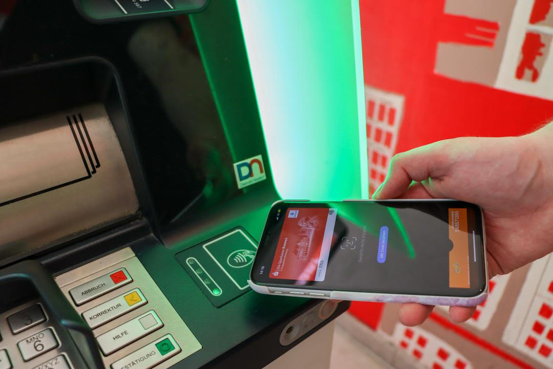 Handy wird an den NFC Bereich eines Geldautomaten gehalten